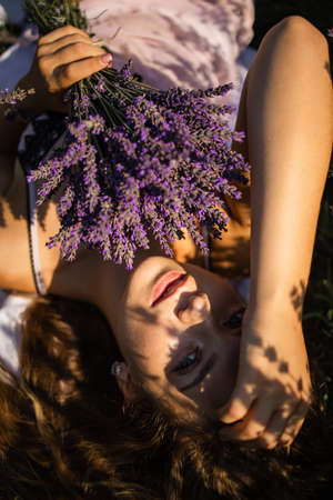 Young Woman In Hat Lying In Lavender Field On Summer Dayの写真素材