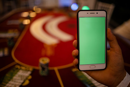 Online Poker Player With A Smartphone At A Casino Tableの写真素材