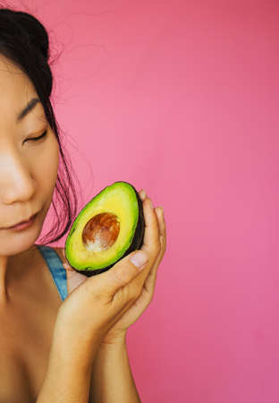Beautiful Asian Woman Holding Avocado Half On Pink Background.の写真素材