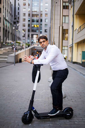 Young Serious Businessman Standing On Electric Scooter In Cityの写真素材