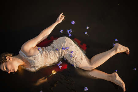 Mysterious And Fashion Portrait Of Young Woman Lying In Water With Faceの写真素材