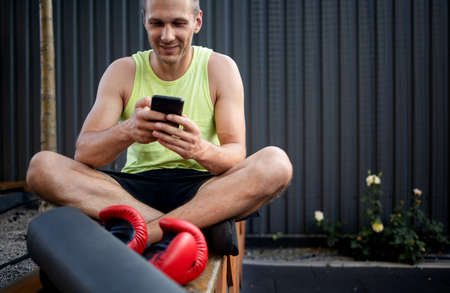 Fitness Sport Man Using Mobile Phone App Relaxing Post-Workout Outdoor.の写真素材