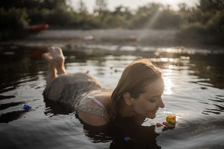 Young Blonde Woman Lying In Water Of A Lake At Sunset.の写真素材