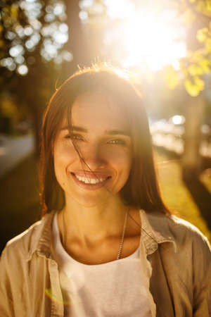 Outdoor atmospheric lifestyle photo of young beautiful lady at sunset. Brown hair and eyes. Warm...