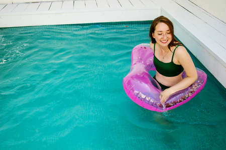 Summer vacation woman in bikini on inflatable donut mattress in swimming pool. girl relaxing sunbathing enjoying travel holidays at resort pool. Luxury lifestyle.の写真素材