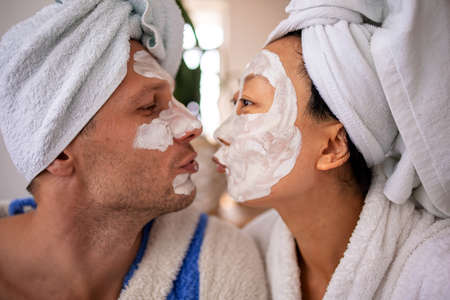 Husband and wife are lying on couch home and doing restoring face masks portrait. Healthy facial skin care at home help conceptの写真素材
