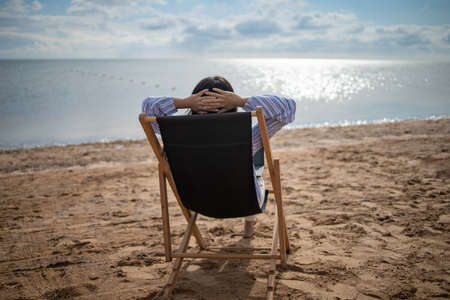Summer beach holiday concept. Young asian woman relax on beach chair. White sand blue sky background with copy space.の写真素材
