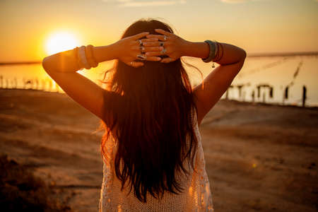 Hippie woman wearing silver rings with stone stands back at sunset. Indie boho vibes and bohemian...
