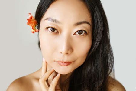Beautiful Young Asian Woman with Clean Fresh Skin on blue background, Facial treatment, Cosmetology, beauty and spaの写真素材