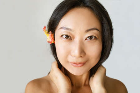 Beautiful Young Asian Woman with Clean Fresh Skin on blue background, Facial treatment, Cosmetology, beauty and spaの写真素材