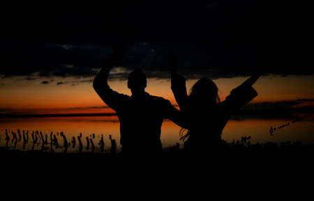 Silhouettes of hugging couple against the sunset sky near sea. Vintage photo.の写真素材