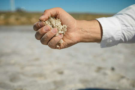 Hands holding Pink Salt deposits on shores of beautiful pink lakeの写真素材