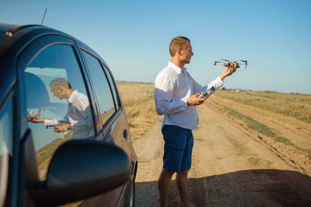 Man holding drone with remote controller in his hands. Guy taking aerial photos and videos