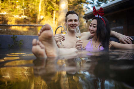 Happy mixed race couple in swimming pool on resort spa pampering romantic weekend getaway for...