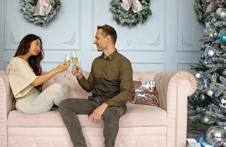 Christmas mixed race couple cheers together near ornate festive Eve. Holidays celebrations family togetherの写真素材