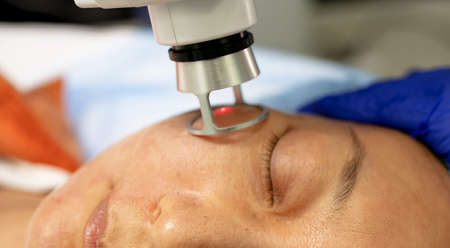 Asian Woman receiving laser and ultrasound facial treatment in a health resort centerの写真素材