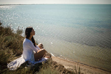 Asian girl sitting on a rock overlooking the ocean in silence