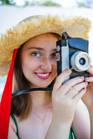young smiling woman taking pictures with retro camera outdoor in summer vacation.の写真素材