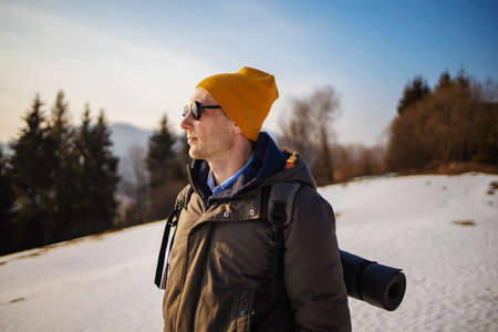 Solo young man traveler camping through an evergreen winter forest in Canada