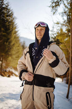 Man with a snowboard standing on a mountain on the background of the winter forest. Winter leisure activity. Healthy lifestyle. Extreme sports.の写真素材