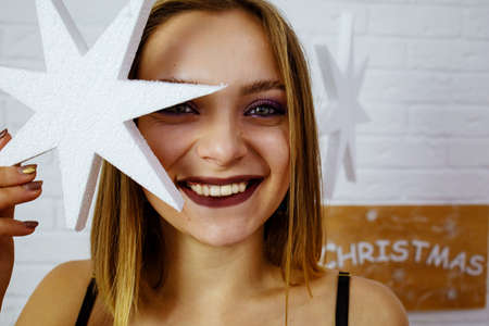 Young pretty woman decorating home for Christmas with star. Magic of winter holidaysの写真素材