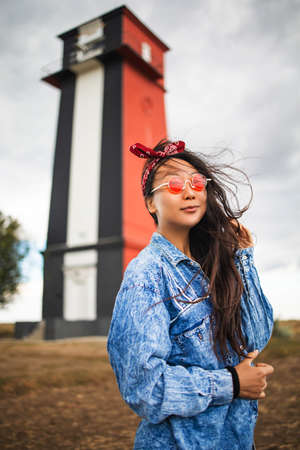 Asian woman sightseeing lighthouse seascape in europe travel outdoor recreation lifestyle concept. girl hair in the wind wearing a denim jacketの写真素材