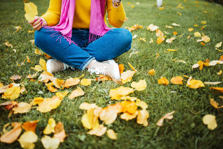 Cute red hair woman in yellow sweater holding autumn leaves in nature.の写真素材