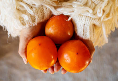 Hand holding persimmon fruit for givingの写真素材