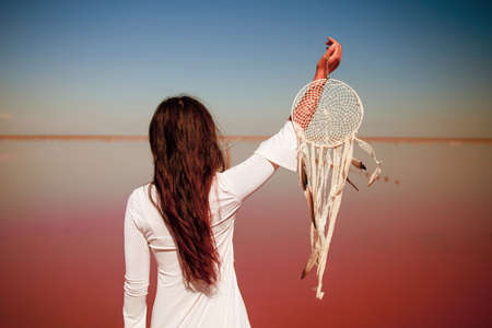 Beautiful asian girl young woman in white dress on the beach of pink lake with dream Catcher, in Boho styleの写真素材