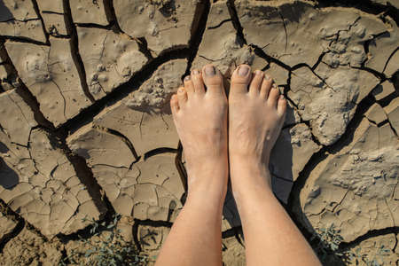 Naked human barefeet on dry soilの写真素材