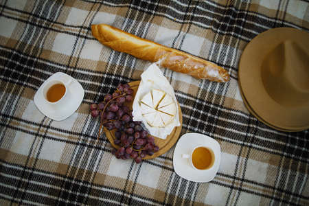 Autumn picnic in park. Plaid with grapes and cheese, coffee cups on golden autumn leaves background top view. Autumn picnic in the park, a warm autumn day.の写真素材