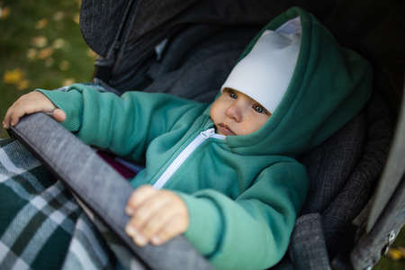 Cute little baby in a stroller outdoor in cold autumn.