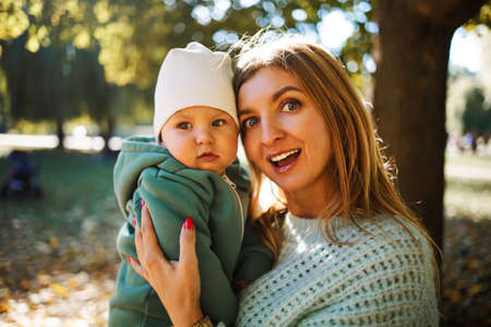 Young beautiful mother and her baby boy, enjoying the autumn day in the parkの写真素材