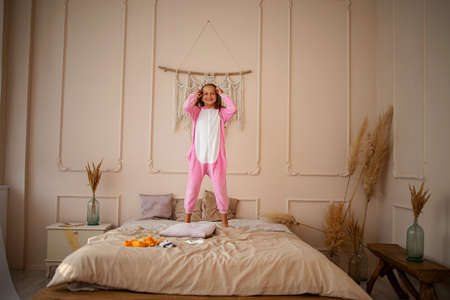 Full length body size view of nice attractive lovely cute childish playful cheerful girl jumping having fun on bed.の写真素材