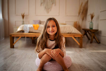 child girl dressed in warm funny pajamas sitting in concrete scandinavian interior bedroom, comfortable scene.の写真素材