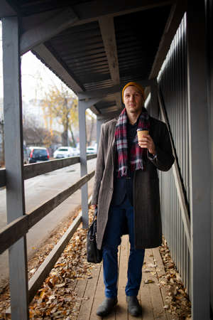 Happy Young Businessman in Casual wear with coffee cup walking by the urban building wall. Lifestyle of Modern People.の写真素材