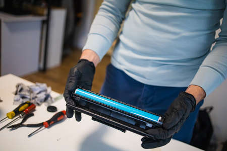 Service center and workshop concept. Man refilling cartridge toner for printer. Ink bottle on white...