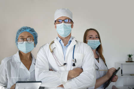 Successful team of doctors looking at camera and smiling while standing in hospitalの写真素材