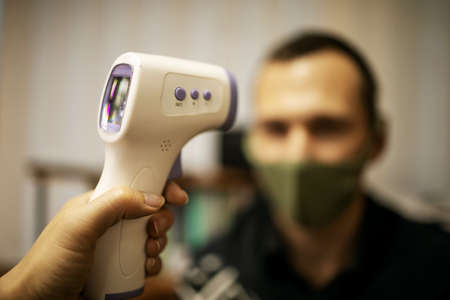 Disease control experts use an Infrared thermometer equipment to check the temperature on the...