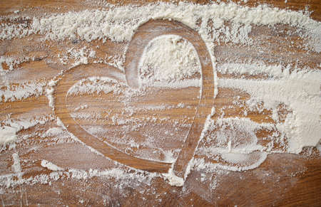 white flour on table. Baking background with heart shape and flour on a dark table. Copy space for textの写真素材