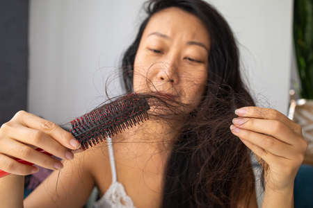 Young asian woman very upset about hair lossの写真素材