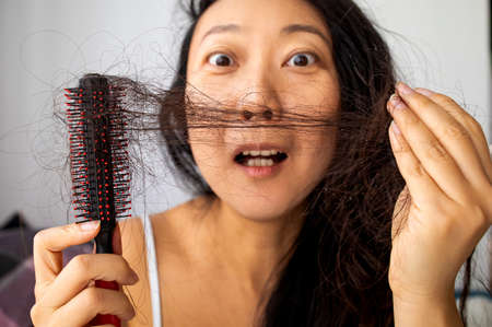 Young asian woman very upset about hair lossの写真素材