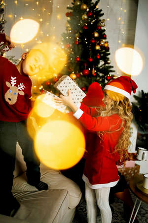Little kids in christmas costume having fun beside a decorated christmas tree. Two kids playing with falling artificial snow flakes near a christmas tree.の写真素材