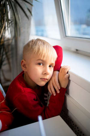 Positive child boy sitting at the window in classroom looking at camera.の写真素材