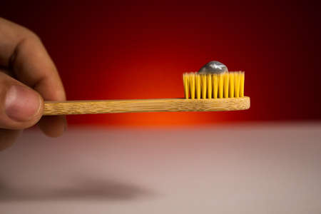 Bamboo toothbrush and toothpaste on red background. Biodegradable personal care products. No plastic concept.の写真素材