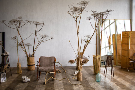 Interior of house is decor in brown tones: wooden chair, knitted pouf, wicker baskets, vases with dried flowers and pampas grass. Dried flowers and vegetation in home interior. Scandinavian cozy decorの写真素材