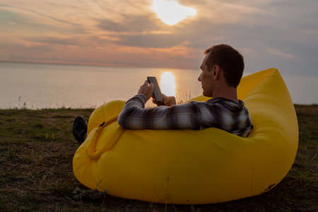 Man using internet on smartphone at sunset on beach.の写真素材