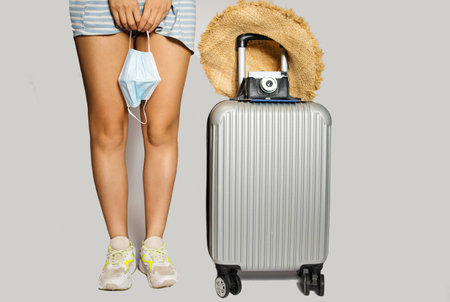 Girl holding Luggage bag and surgical face mask on white background. protection Coronavirus disease (Covid-19) infection. New Normal and travel bubble conceptsの写真素材