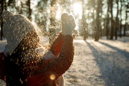 Asian girl enjoys winter, frosty day, snow. playing with snow, a woman throws white, loose snow into...