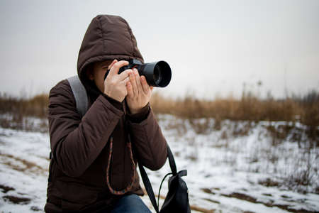 Man photographer looking at camera and taking picture on digital camera Is snowing and man is...
